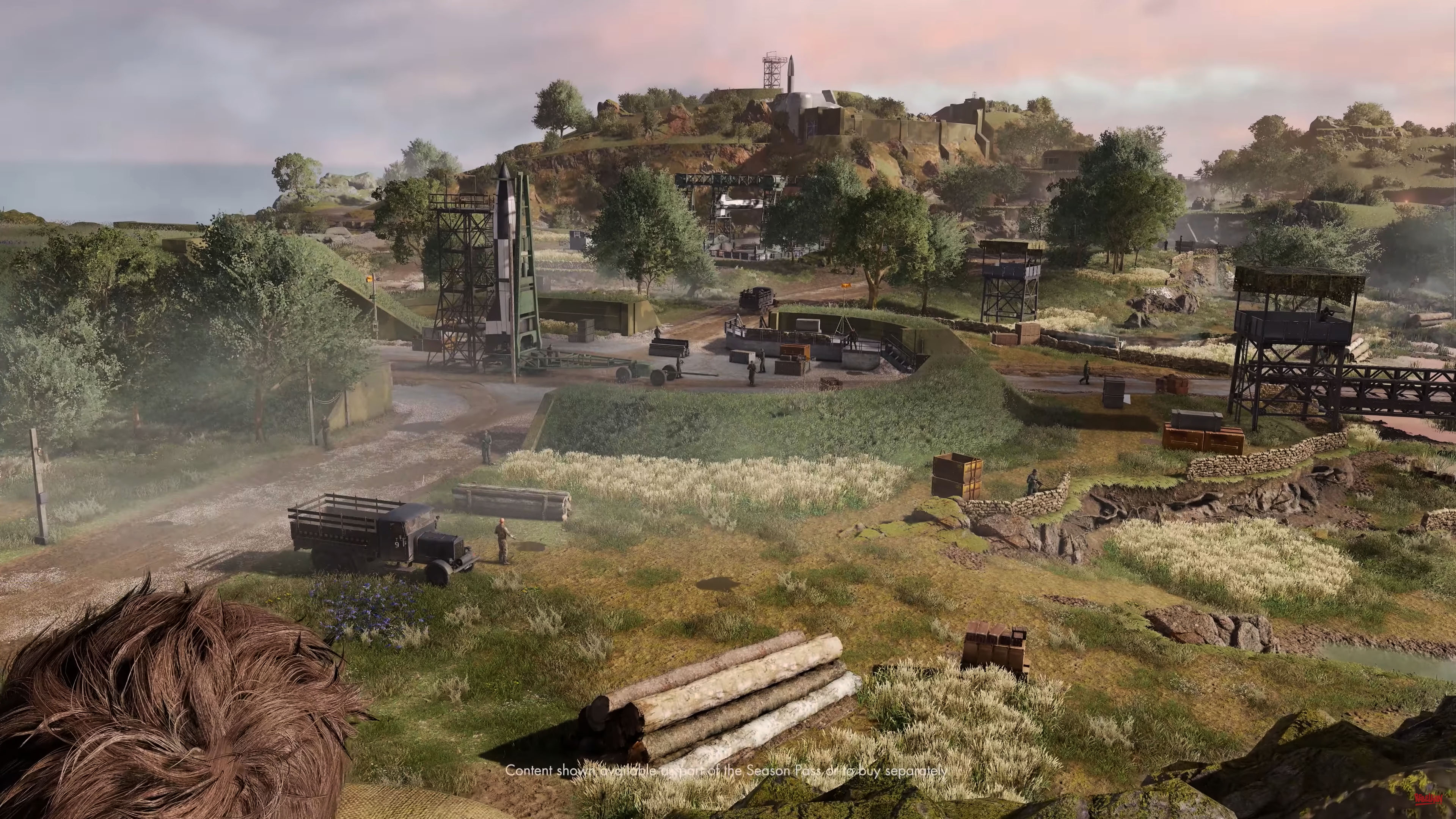 An upper angle camera, looking at a V-2 rocket site. It’s masked by concrete structures that are painted in green camouflage. On top, lots of lush grass is spread, further hiding the rocket sites.